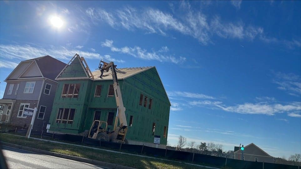 Residential home framing with green weather barrier and equipment